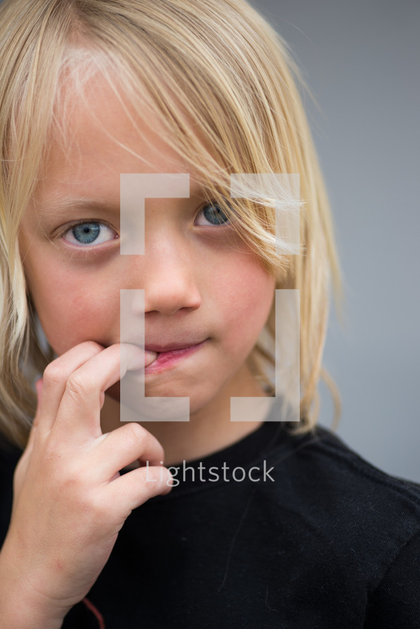 a boy child biting his fingers 