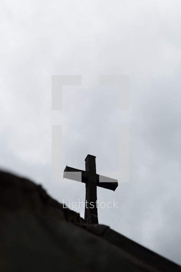 The silhouette of a cross against a gray sky.