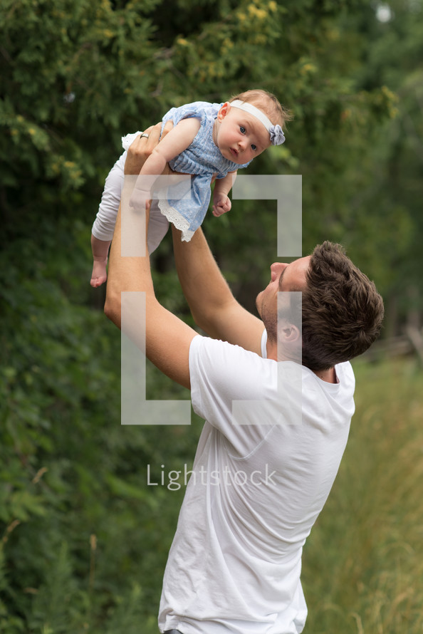 father holding up his infant daughter 