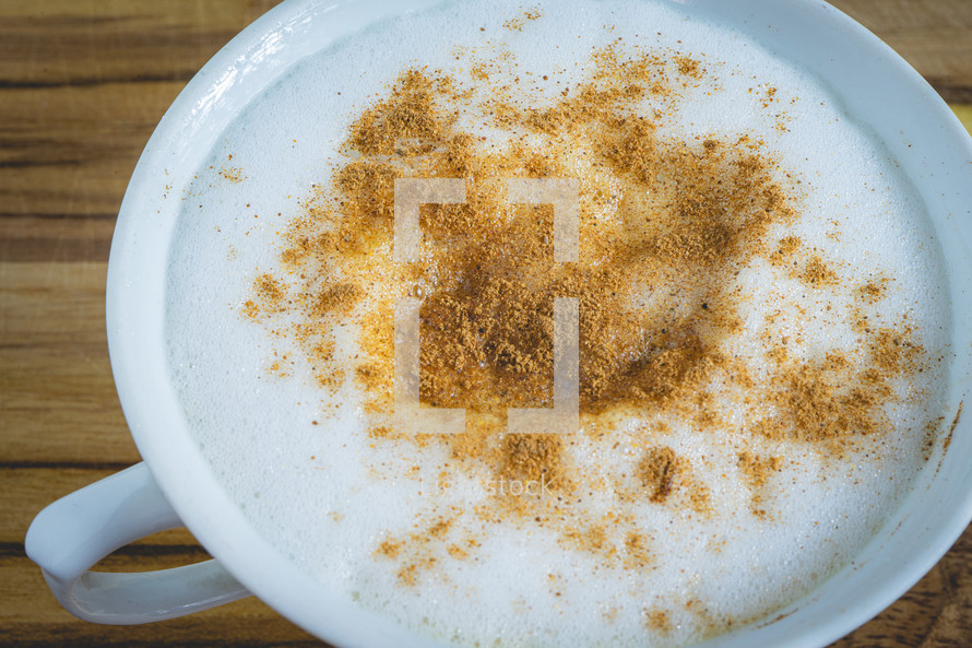 Delicious home made Cappuccino, in a white cup, on a wooden table. Home made Coffee.