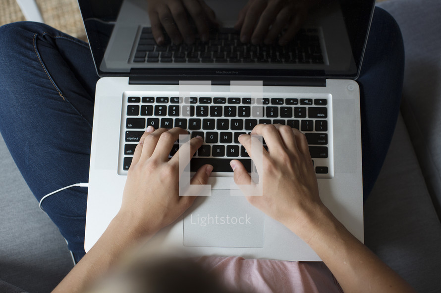 a woman sitting on a couch while typing on a laptop computer 