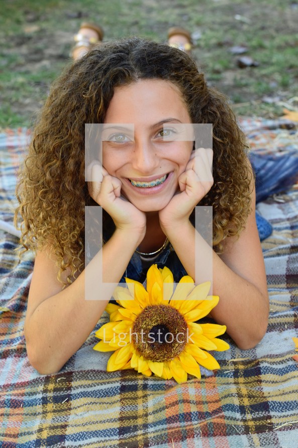 smiling teen girl laying on a plaid blanket 