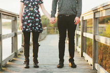 a couple standing on a bridge holding hands 