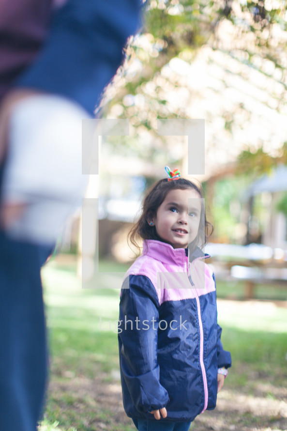 a little girl in a jacket standing outdoors 