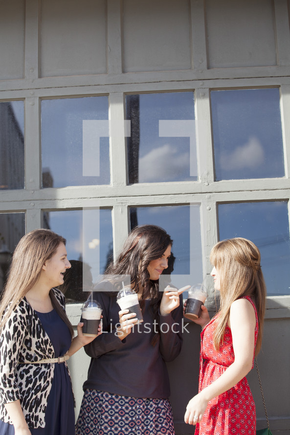 Group of women holding frozen latte drinks.