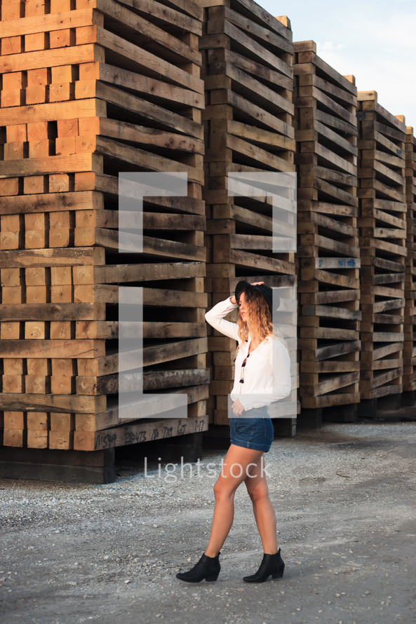 woman posing in front of stacked pallets 
