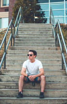 young man sitting on concrete steps at school 