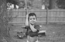 a toddler hanging onto a rope 