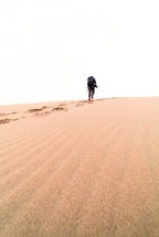a man climbing up a sand dune 