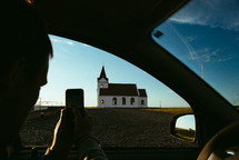 a man taking a picture of a rural church 