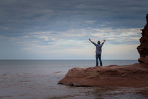 a man with raised arms on a beach 