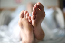 Feet of a woman lying in bed.