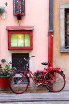 Red ladies bicycle and flower pots outside pink painted shop