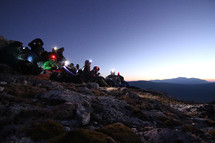 hikers with headlamps sitting on a mountainside 
