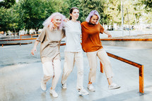 Modern teenage girls with colorful dyed hair in park. Women chatting, gossiping and laughing. Friendship concept. High quality photo