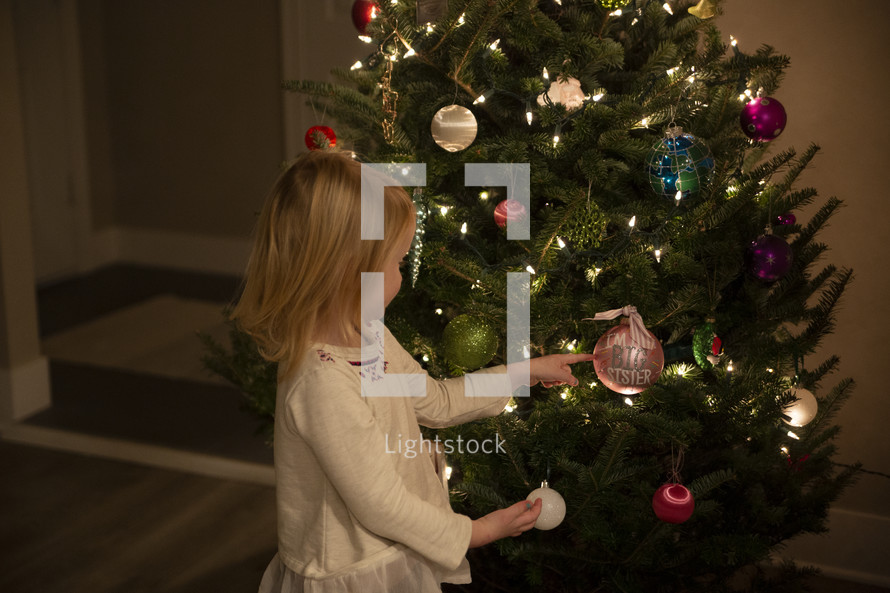 Small child holding a "big sister" ornament