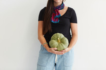 a woman holding a green pumpkin 