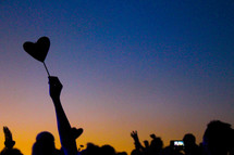 silhouette of hands in a crowd and heart balloon