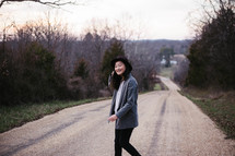 portrait of a young woman crossing a dirt road 