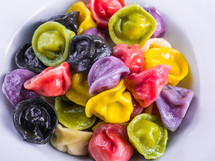 Homemade dumpling, traditional East European food. Colorful ravioli for kids in a white bowl