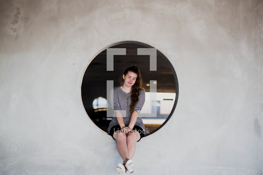 portrait of a teen girl sitting in a port hole window 
