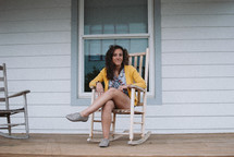 a teen on a front porch sitting in a rocking chair 