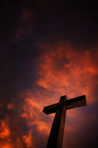 Cross under fire red storm clouds at night.