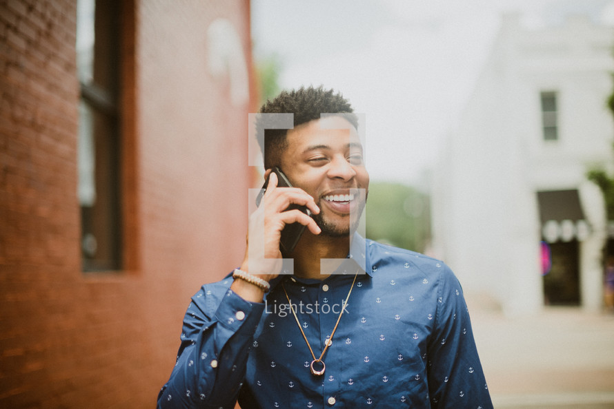 a smiling man talking on a cellphone 