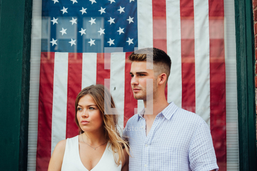 a couple standing in front of an American flag 