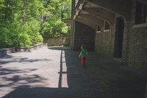 toddler girl walking outdoors near an old stone old 