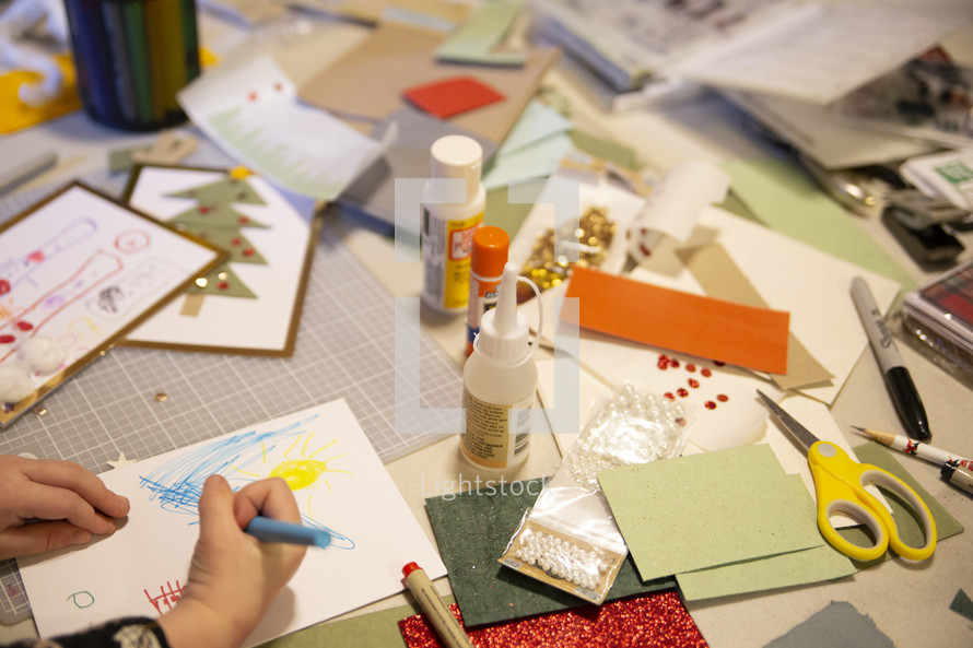Child hand and craft supplies for making Christmas cards