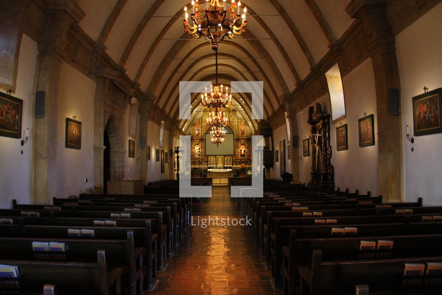 A church sanctuary with a curved ceiling and chandeliers.
