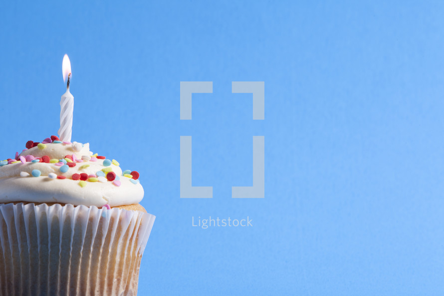 cupcake with a candle against a blue background 