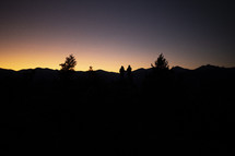 silhouette of friends standing outdoors at dusk on a mountain 