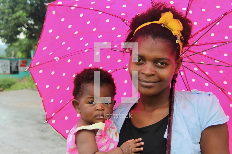 An African mother holding her infant daughter under an umbrella 
