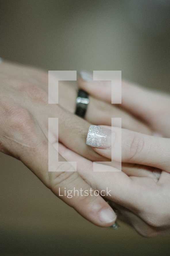 Woman's hand placing a ring on a man's finger.