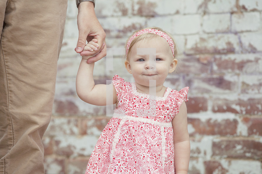 Father holding toddler daughter's hand.