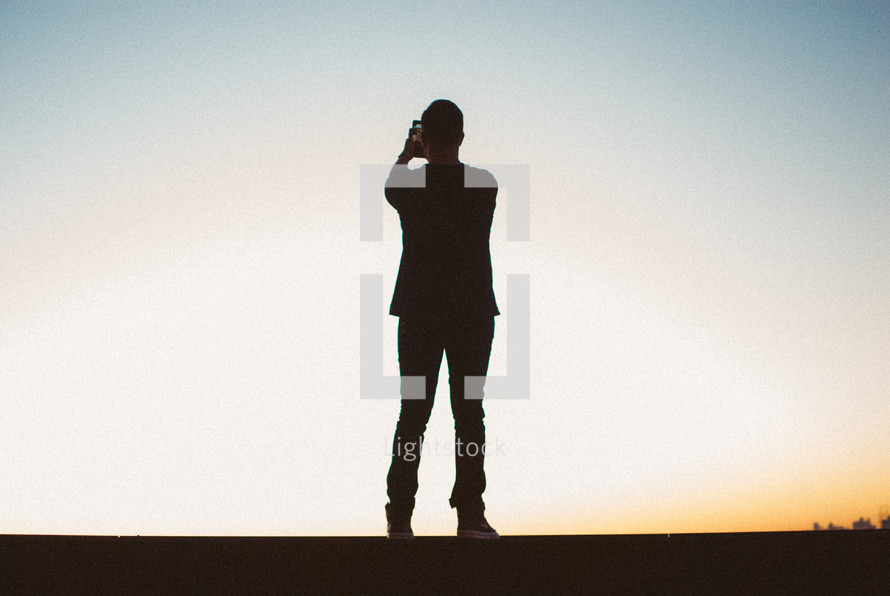 silhouette of a man holding a camera 