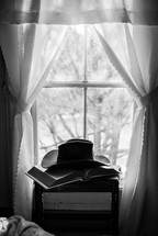 cowboy hat on a Bible in front of a window 