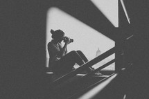 silhouette of a teen girl on a staircase holding a camera 