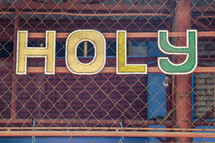 word Holy on a chain link fence 