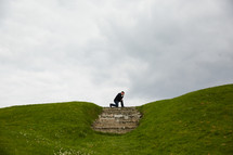 a man kneeling in prayer at the top of a hill 