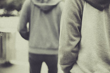 torsos of men in hoodies walking 