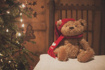 a holiday bear on a table and Christmas tree