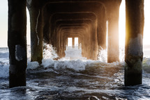 waves crashing under a pier 