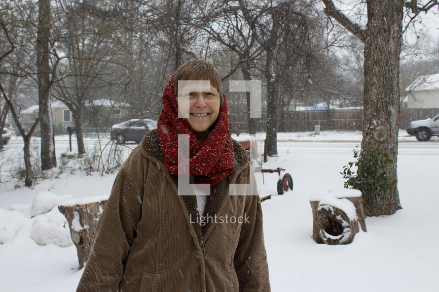 a woman in a scarf standing outdoors in the snow 