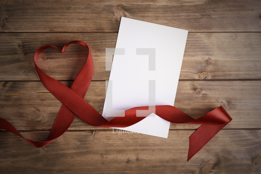 red ribbon in the shape of a heart and blank paper 
