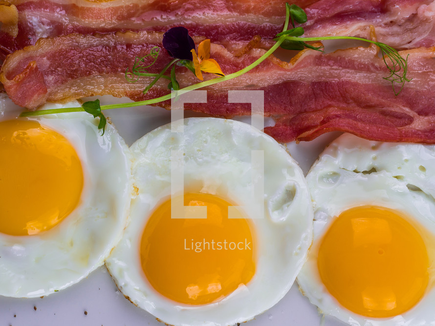 Fried eggs with bacon on white plate. Delicious, colorful breakfast.
