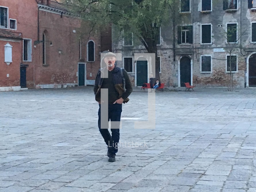 a man walking in an empty courtyard 