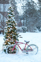 bicycle leaning against a tree in the snow 